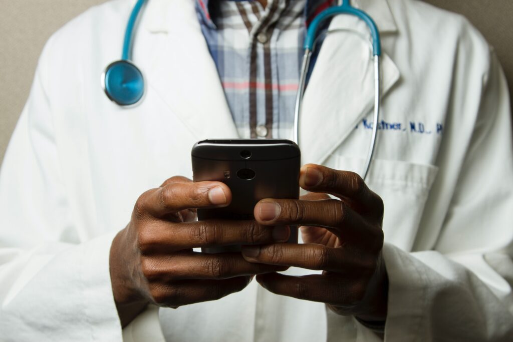 doctor wearing stethoscope and holding a phone with both hands